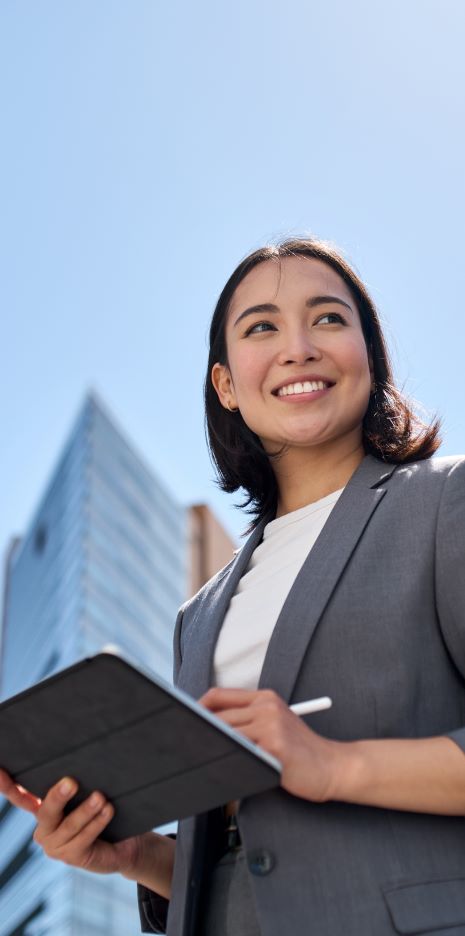 woman in a blazer smiling while holding a tablet